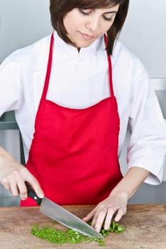 Female chef chopping cilantro leaves with a knife