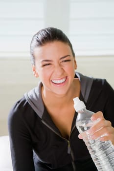 Close_up of a young woman holding a water bottle and smiling