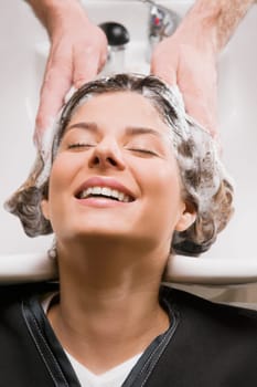 Young woman getting hair shampooed at the hair salon