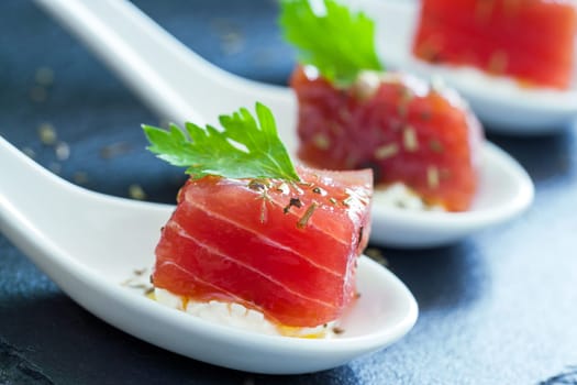 Extreme close up of appetizing tuna morsel on white ceramic spoon.