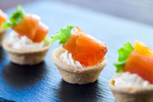 Macro close up of Appetizing Mini puff smoked salmon pastry tartlets for catering.