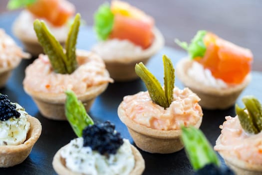 Macro close up of Multiple mini pastry tartlets with variety of seafood filling.