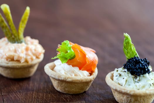Macro close up of three Mini puff pastry tartlets with seafood filling. Tartlets filled with smoked salmon,cottage cheese, creamy crab and beluga fish caviar.
