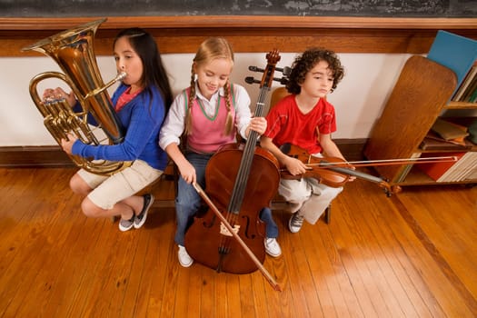 Three students playing musical instruments in a classroom
