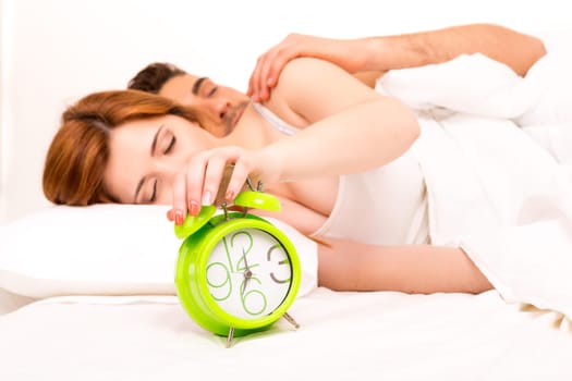 Couple is sleeping and the alarm clock starts to ring - time to wake up!