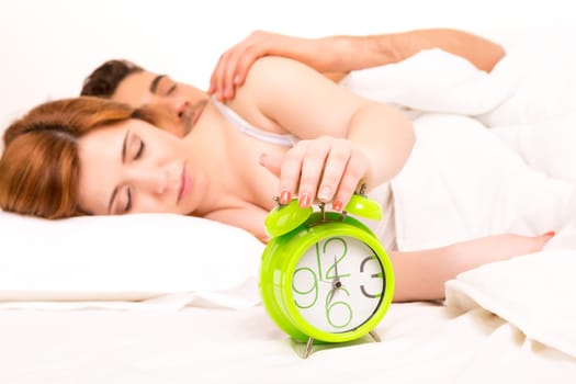 Couple is sleeping and the alarm clock starts to ring - time to wake up!