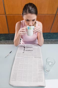 High angle view of a businesswoman drinking coffee and reading a newspaper