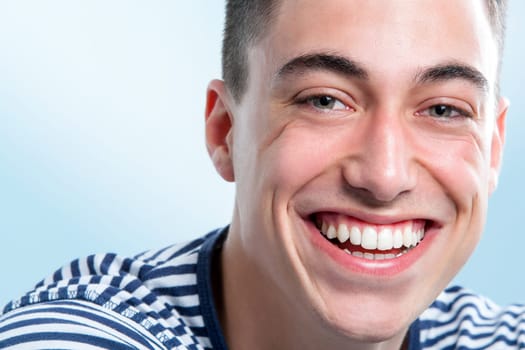 Extreme close up face shot of Young man with charming and healthy toothy smile.