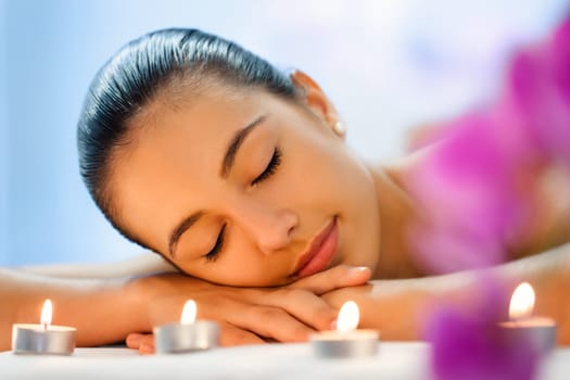 Close up portrait of Young woman relaxing in dimmed candle light after massage.
