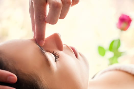 Macro close up of  relaxing facial massage. Therapist applying pressure with fingers between eyes.