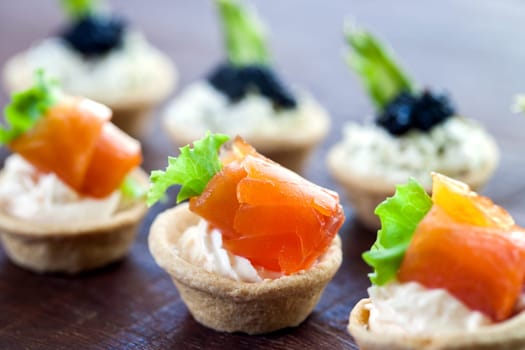 Macro close up of Multiple mini seafood pastry tartlets.Variety of smoked salmon and savory open pastry tartlets.