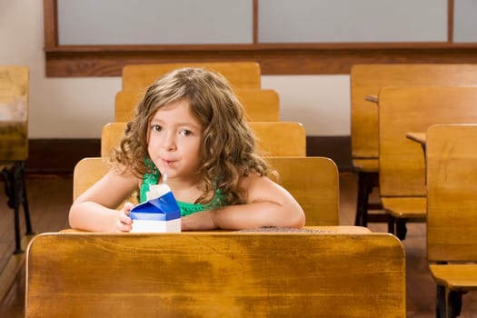 Schoolgirl drinking juice in a classroom