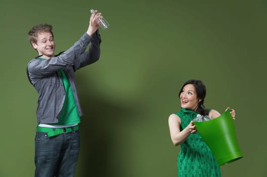 Woman holding a recycling bin and a man throwing an empty water bottle