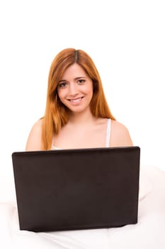 Young beautiful woman having breakfast in bed while working or relaxing with her computer