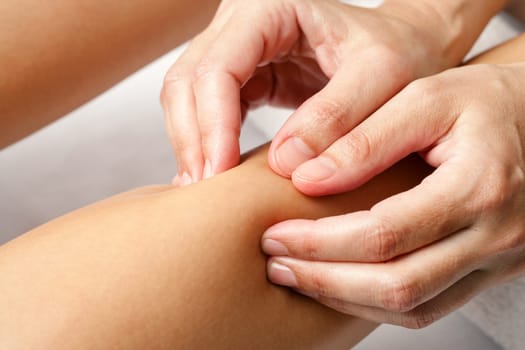 Macro close up of hands doing rehabilitation massage on female calf muscle.