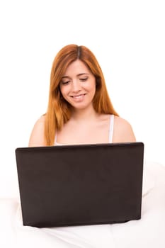 Young beautiful woman having breakfast in bed while working or relaxing with her computer