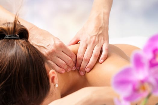 Macro close up of hands massaging female neck and shoulders.