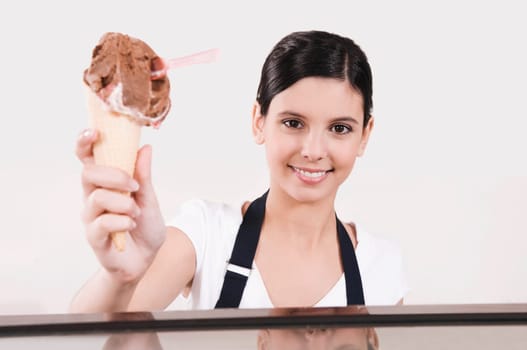 Female ice cream seller holding a cone of an ice cream