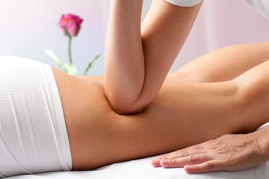 Close up of therapist applying pressure on female hamstrings with elbow.