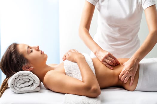 Close up of osteopath doing manipulative massage on female abdomen.