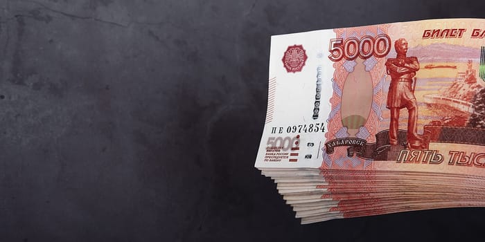 Russian cash banknotes of five thousand rubles, the bundle hangs on a gray background, there is a place for the inscription and text. Layout, mockup.