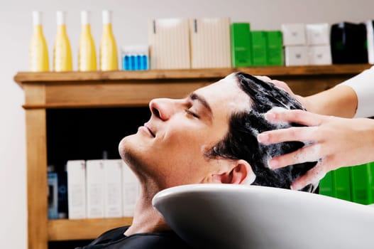 Mid adult man getting hair shampooed at salon