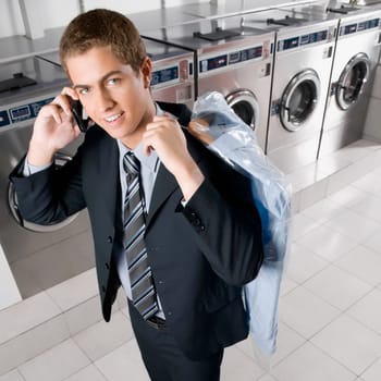 Businessman talking on a mobile phone in a laundromat