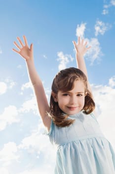 Low angle view of a girl smiling with her arms raised