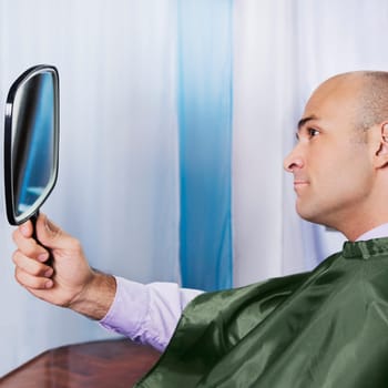 Man looking himself in a mirror after a haircut