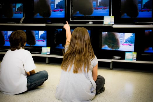 Rear view of a boy and a girl watching television in a supermarket