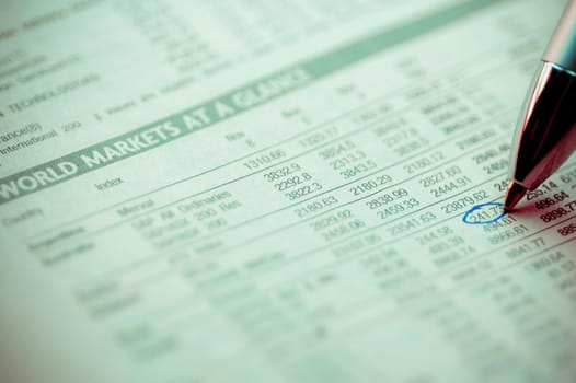 Close_up of a ball point pen marking on a financial newspaper