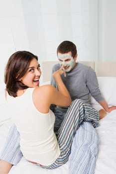 Portrait of a young woman applying facial mask on a young manŽs face