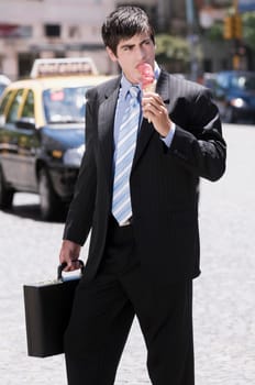 Businessman eating an ice cream on the road