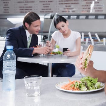 Couple text messaging on a mobile phone in a restaurant