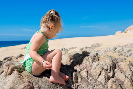 Baby girl sitting on a rock, Cabo San Lucas, Mexico