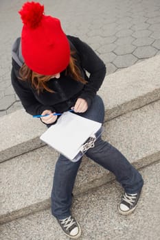 High angle view of a young woman sitting on steps and reading papers