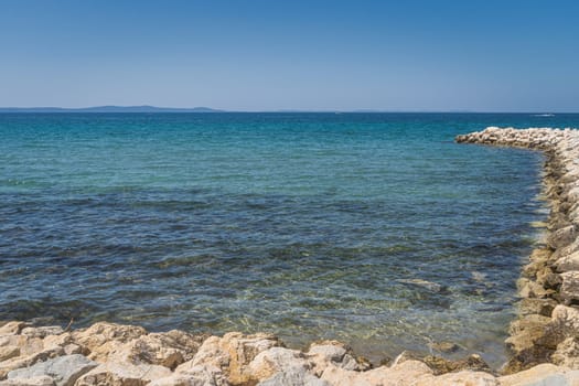 Calm, turquoise clouded and crystal clear waters of Adriatic Sea with rocky pier in Zaton bay, Croatia