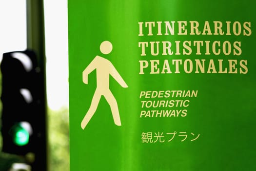 Close_up of a pedestrian walkway sign with a traffic light in the background, Madrid, Spain