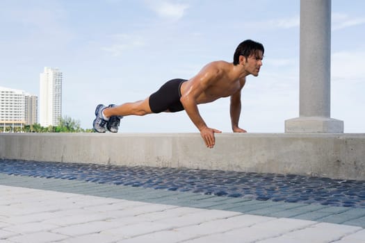 Young man doing push ups on the ledge