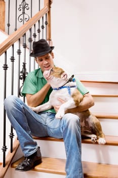 Man sitting on a staircase and carrying his dog