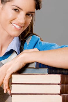 Portrait of a teacher with a stack of books in a classroom