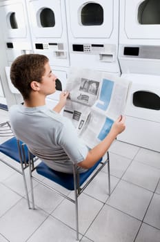 Man reading a newspaper in a laundromat