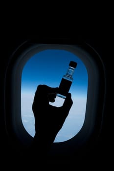 PersonŽs hand holding a bottle in front of an airplane window
