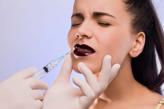 Close_up of a surgeonŽs hand injecting on a young womanŽs lips
