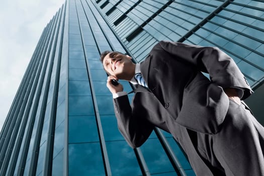 Low angle view of a businessman talking on a mobile phone and smiling