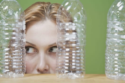 Close_up of a womanŽs face behind three plastic bottles