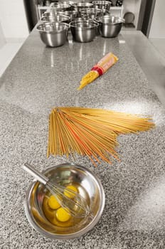 Egg yolk and an egg beater in a bowl with spaghetti