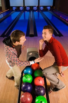 Two young men dancing in a bowling alley