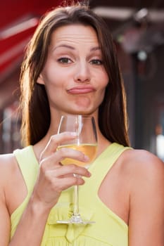 Portrait of a young woman holding a glass of wine and making a face