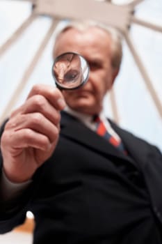 Low angle view of a businessman holding a magnifying glass
